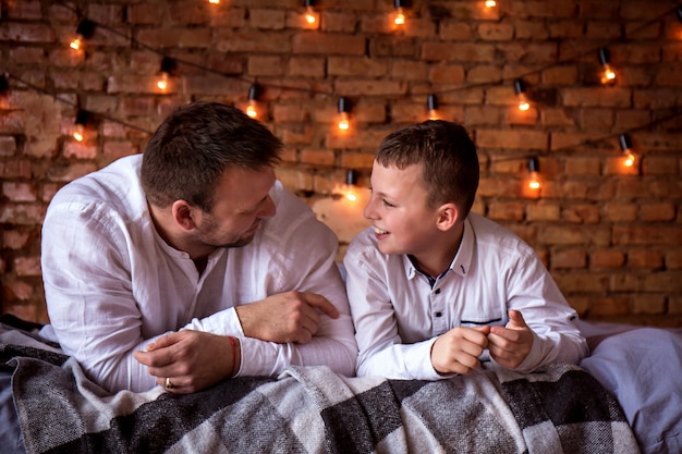 Vater und Sohn, die zu Hause reden, liegen im Bett