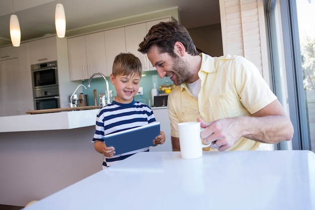 Vater und Sohn, die zu Hause Tabletten-PC im Wohnzimmer verwendet