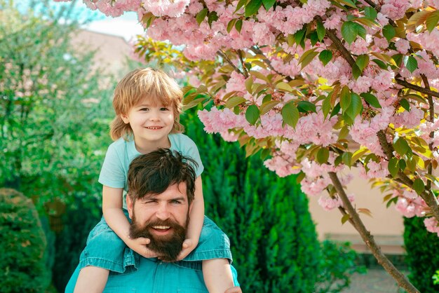 Vater und Sohn entspannen sich zusammen Glücklicher Vater, der Schulterfahrt auf seinen Schultern im Garten gibt Glücklicher Vatertag