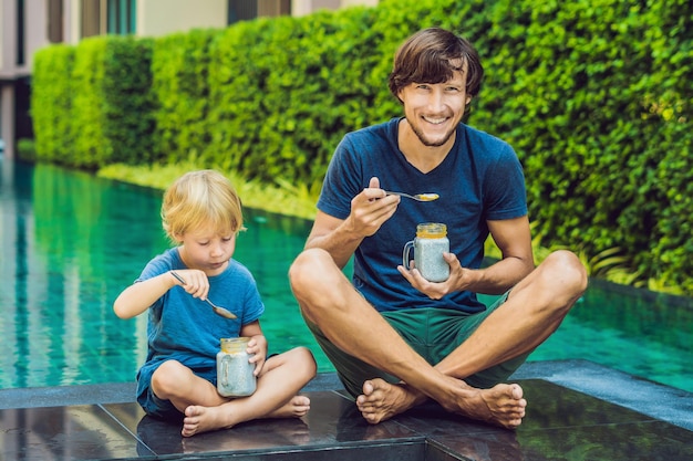 Vater und Sohn essen morgens Dessert mit Chiasamen und Mangos am Pool. gesunde Ernährung, vegetarisches Essen, Ernährung und Menschenkonzept.