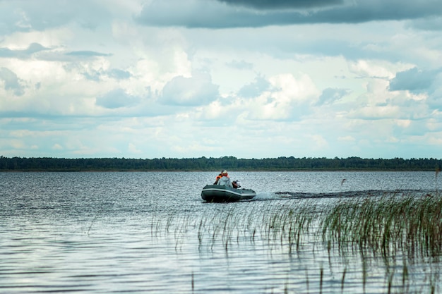 Vater und Sohn fahren mit einem Motorboot auf dem See.