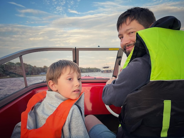 Vater und Sohn fahren Motorboot mit Sicherheitswesten und fahren in der Newa Sankt Petersburg