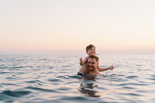 Vater und Sohn genießen ein Schwimmen im Ozean in der Dämmerung