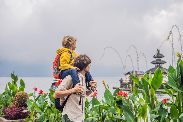 Vater und Sohn im Hintergrund des hinduistischen Tempels Pura Ulun Danu Bratan Bali, umgeben von Blumen an