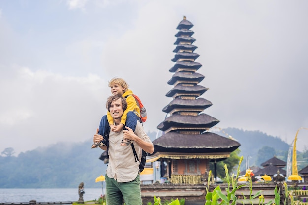 Vater und Sohn im Hintergrund des hinduistischen Tempels Pura Ulun Danu Bratan Bali, umgeben von Blumen an