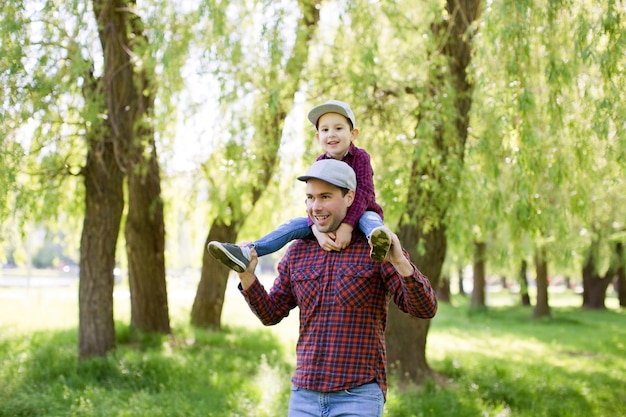 Vater und Sohn in roten Hemden gehen im Frühlingspark Glückliches Vatertagskonzept