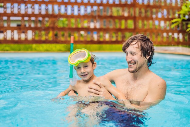 Vater und Sohn in Schwimmbrillen haben Spaß im Pool