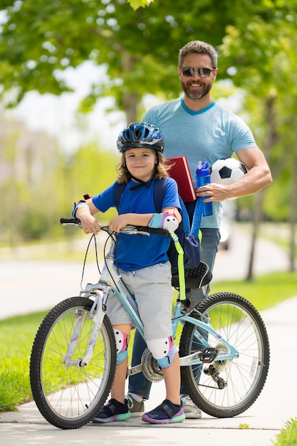 Vater und Sohn Konzept Vater unterrichtet Sohn in Schutzhelm Radfahren Vater hilft Sohn bekommen