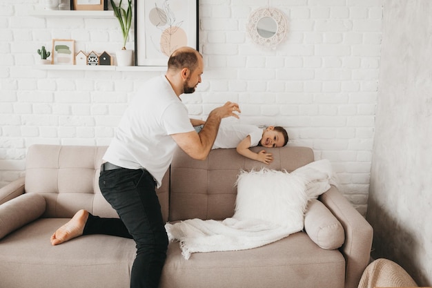 Vater und Sohn lächeln, während sie Zeit miteinander verbringen Vater und Sohn spielen zu Hause