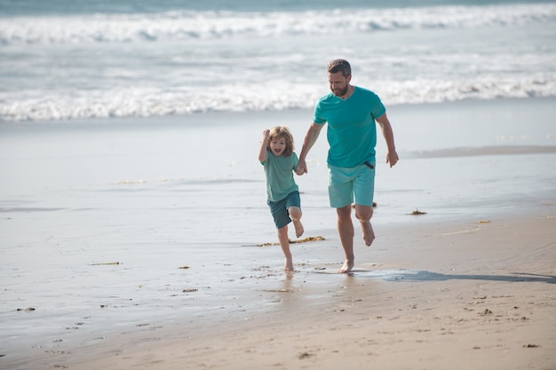 Vater und Sohn laufen am Sommerstrand, Papa und Kind haben Spaß im Freien