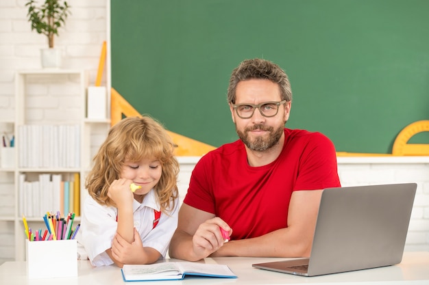 Vater und Sohn lernen im Klassenzimmer mit Laptop, Schule online.