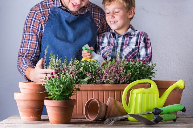 Vater und Sohn machen zu Hause einen städtischen Garten. Aktivität, die die geistige und geistige Gesundheit anregt. Pflanzen und Wachsen von Herbstblumen, umweltfreundliches Hobby und Freizeit, Familienzeitkonzept.