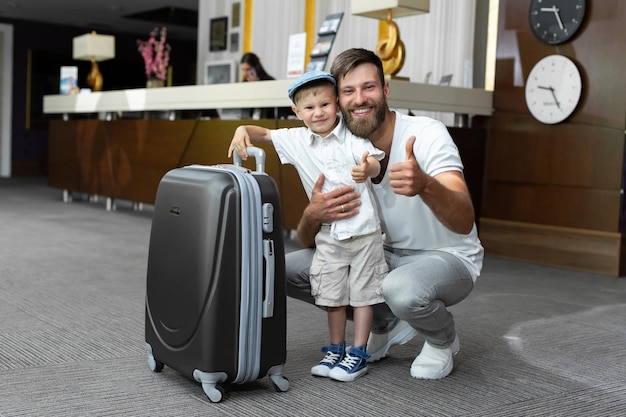 Vater und Sohn mit Koffer an der Hotelrezeption