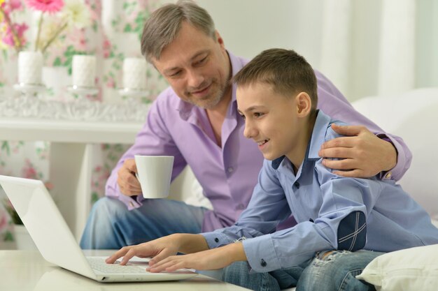 Vater und Sohn mit Laptop am Tisch