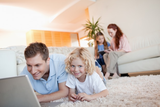 Vater und Sohn mit Laptop auf dem Boden