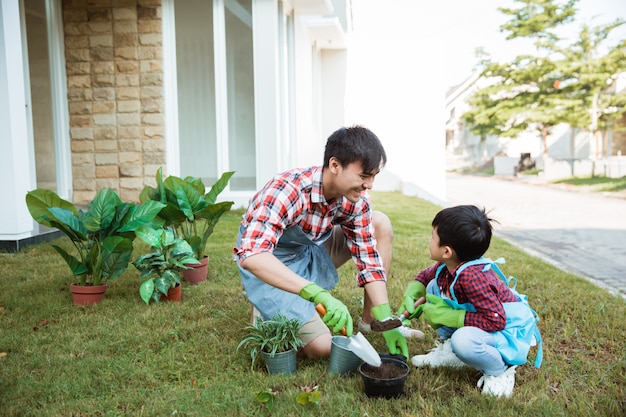 Vater und Sohn pflanzen gemeinsam eine Pflanze im Garten ihres Hauses