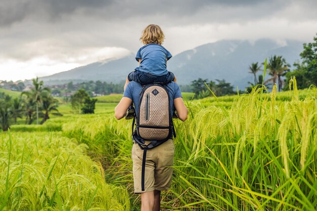 Vater und Sohn Reisende auf den wunderschönen Reisterrassen von Jatiluwih vor dem Hintergrund berühmter Vulkane in Bali, Indonesien Reisen mit Kindern Konzept