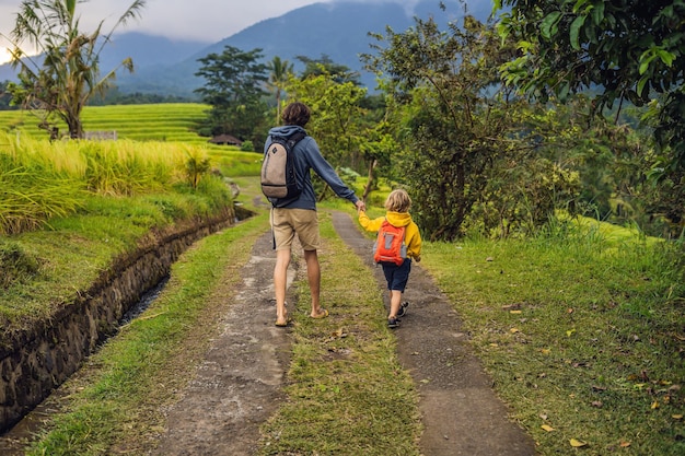 Vater und Sohn Reisende auf den wunderschönen Reisterrassen von Jatiluwih vor dem Hintergrund berühmter Vulkane in Bali, Indonesien Reisen mit Kindern Konzept