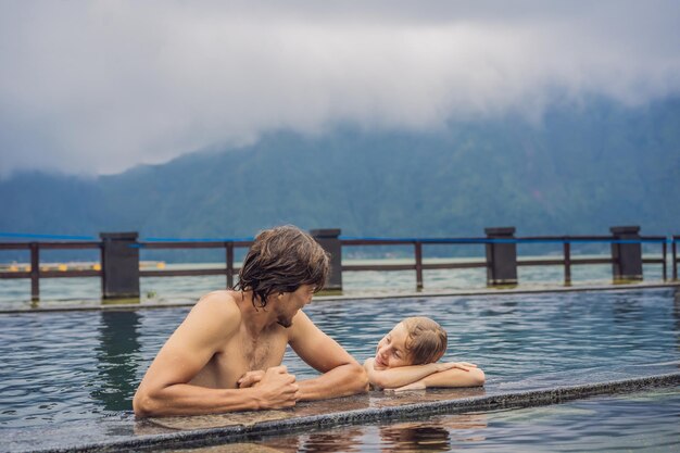 Foto vater und sohn reisende in hot springs in bali auf dem hintergrund des sees reisen mit kindern konzept