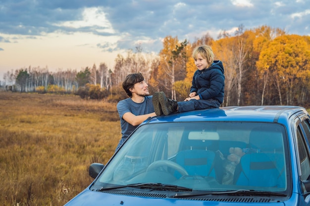 Vater und Sohn ruhen sich auf einem Roadtrip am Straßenrand aus. Autoreise mit Kinderkonzept.