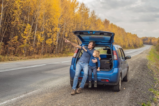 Vater und Sohn ruhen sich auf einem Roadtrip am Straßenrand aus. Autoreise mit Kinderkonzept.