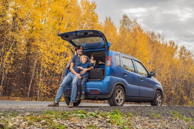 Vater und Sohn ruhen sich auf einem Roadtrip am Straßenrand aus. Autoreise mit Kinderkonzept.