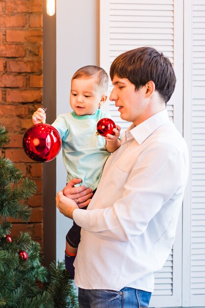 Vater und Sohn schmücken den Weihnachtsbaum im Wohnzimmer