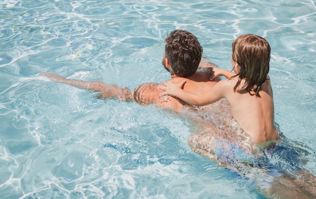 Vater und Sohn schwimmen im Pool Sommerfamilie Kind-Pool-Party Familienfreizeit Sommerurlaub Vater und Sohn im Pool Kind mit Papa spielt im Schwimmbad