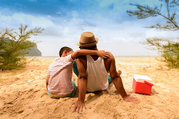 Vater und Sohn sind glücklich für Picknick mit Blick aufs Meer.