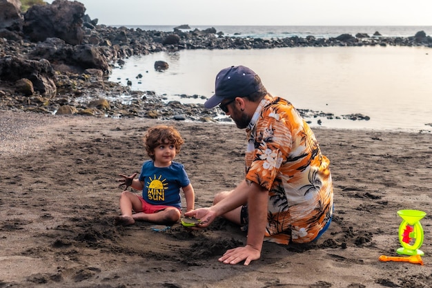 Vater und Sohn spielen am schwarzen Sandstrand von Valle Gran Rey auf den Kanarischen Inseln La Gomera