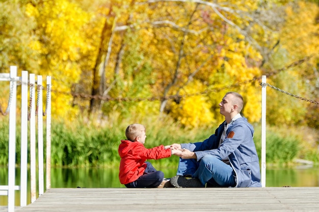 Vater und Sohn spielen auf dem Pier Sonnige Herbstseitenansicht