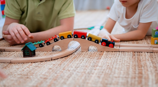 Vater und Sohn spielen auf einer Holzspielzeugbahn im Spielzimmer.