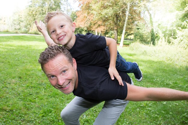 Vater und Sohn spielen bei Sonnenuntergang im Park. Leute, die Spaß auf dem Feld haben. Konzept der freundlichen Familie und des Sommerurlaubs