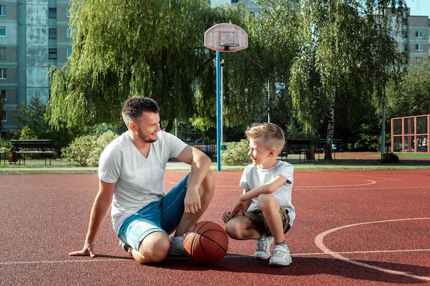 Vater und Sohn spielen gemeinsam Basketball auf dem Basketballplatz