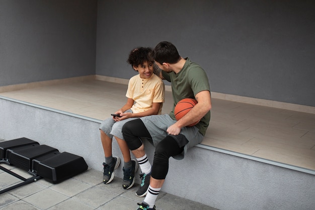 Foto vater und sohn spielen gemeinsam basketball im hinterhof