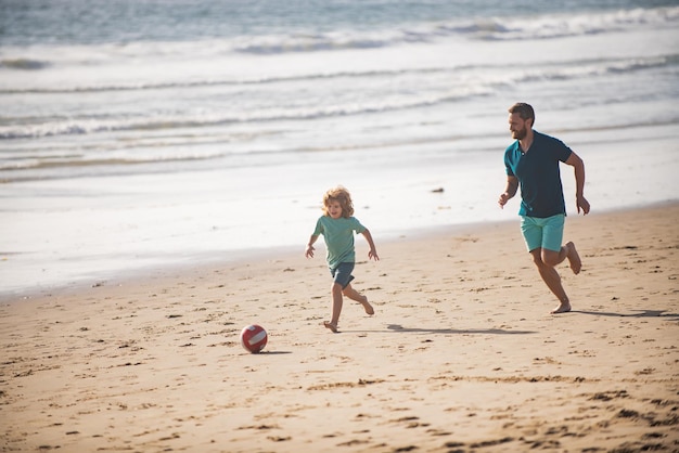 Vater und Sohn spielen im Sommerurlaub mit der Familie Fußball oder Fußball am Strand Vater und Kind spielen