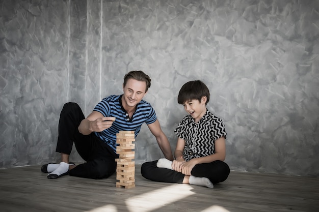 Vater und Sohn spielen Jenga im Haus. Glückliches Familienkonzept.