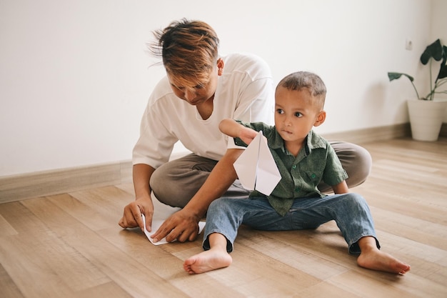 Vater und Sohn spielen mit Papierflieger und lächeln, während sie zu Hause Zeit miteinander verbringen