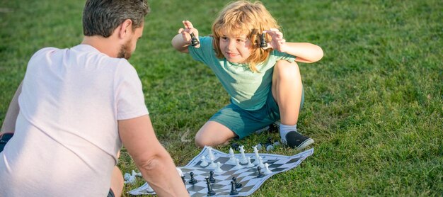 Foto vater und sohn spielen schach outdoor-banner-poster mit kopierraum glückliche familienelternschaft und schachmatt in der kindheit, die zeit miteinander verbringen