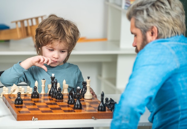 Vater und Sohn spielen Schachlehrer und helfen seinem Schülerjungen beim Schach im Bildungsunterricht