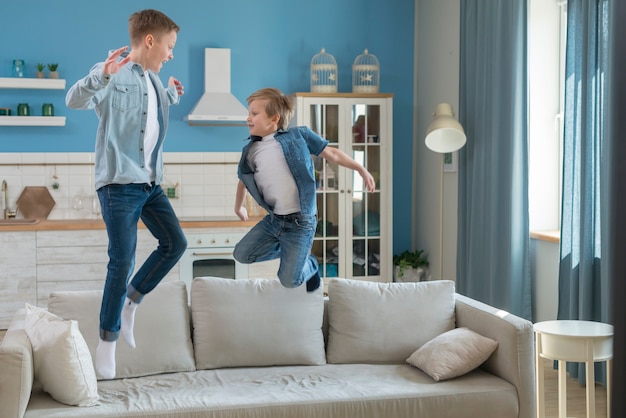 Foto vater und sohn springen auf das sofa