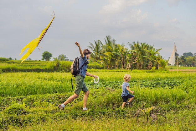 Vater und Sohn starten einen Drachen in einem Reisfeld in Ubud, Insel Bali, Indonesien