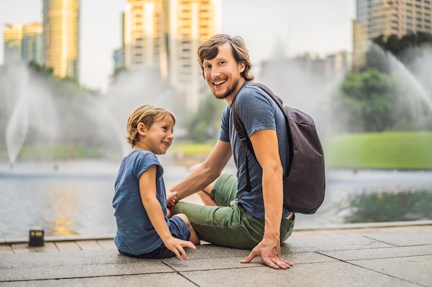 Vater und sohn touristen auf dem hintergrund des brunnens auf dem see in der nacht in der nähe von twin towers mit stadt im hintergrund kuala lumpur malaysia