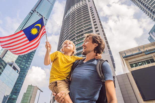 Vater und Sohn Touristen in Malaysia mit der Flagge Malaysias in der Nähe der Wolkenkratzer Reisen mit Kinderkonzept