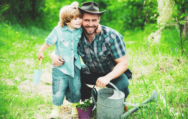 Foto vater und sohn verbringen gemeinsam freizeit im garten und umarmen den sohn, der seinem vater hilft, den tr zu pflanzen