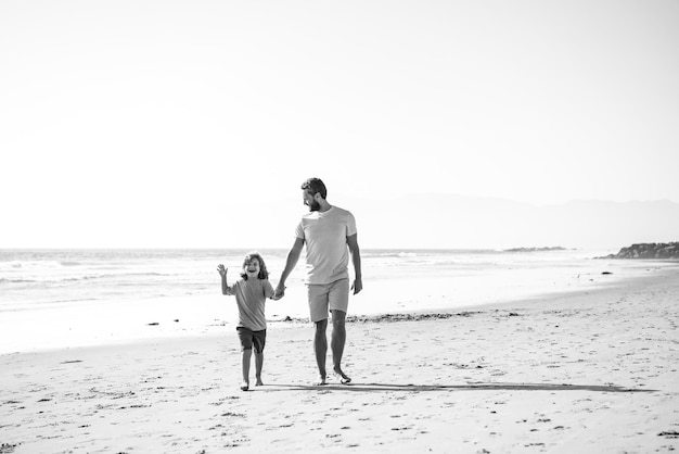 Vater und Sohn zu Fuß am Sommerstrand Vater und Kind spielen im Freien