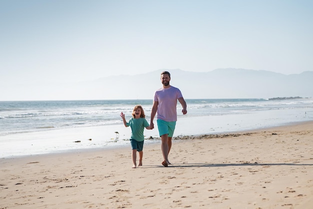 Vater und Sohn zu Fuß auf dem Meer Vater und Kind halten sich an den Händen und gehen zusammen Glückliches Familienkonzept