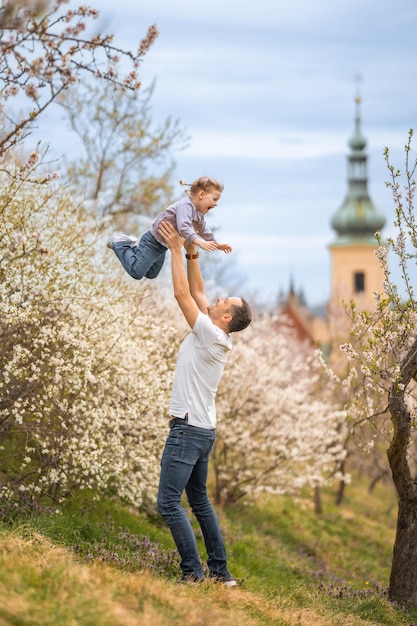 Vater und Tochter amüsieren sich gemeinsam unter einem blühenden Baum im Frühlingspark Petrin in Prag Euro