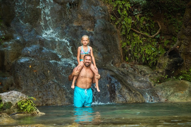 Vater und Tochter an einem Wasserfall im Dschungel. Reisen in die Natur in der Nähe eines schönen Wasserfalls, Türkei.