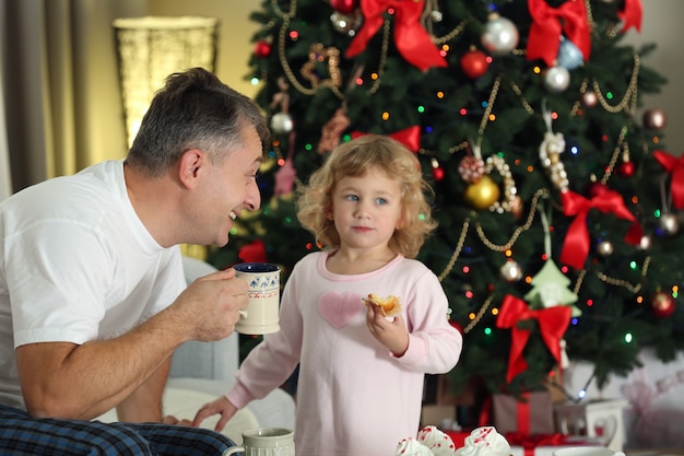 Vater und Tochter auf Weihnachtsinnenhintergrund